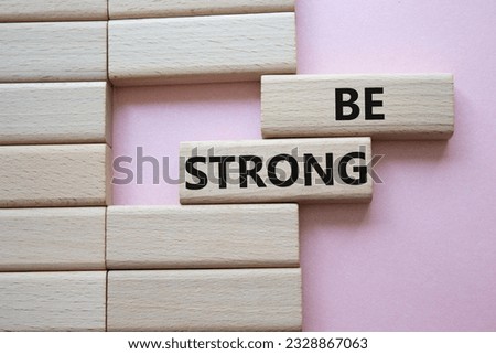 Be strong symbol. Wooden blocks with words Be strong. Beautiful pink background. Business and Be strong concept. Copy space.