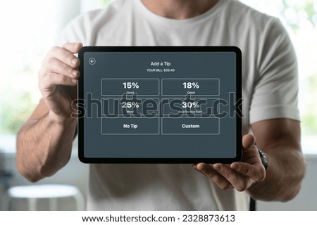 Man holding a tablet with tipping screen inside a restaurant Royalty-Free Stock Photo #2328873613