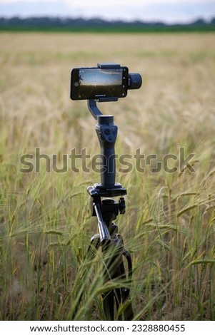 Steadicam for a phone on a tripod in a wheat field.
