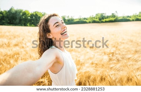 Happy woman with arms outstretched enjoying freedom in a wheat field - Joyful female breathing fresh air outside - Healthy life style, happiness and mental health concept Royalty-Free Stock Photo #2328881253