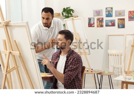 Artist teaching his student to paint in studio. Creative hobby