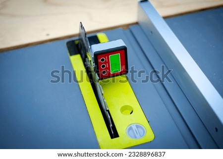 Brand-new table saw with digital level box inclinometer showing 0-degree angle attaches to steel blade and aluminum fence. Protractor bevel gauge for absolute measurements woodworking carpentry