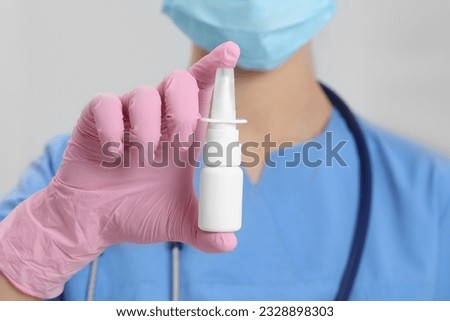 Doctor holding nasal spray on white background, closeup Royalty-Free Stock Photo #2328898303