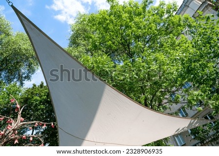 Triangular sun canopy in summer garden, trees and sky Royalty-Free Stock Photo #2328906935