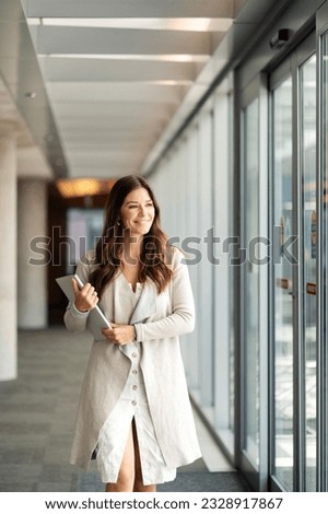 Portrait of beautiful smiling businesswoman holding laptop in modern office, looking away. Successful woman with long hair in casual clothes working. Fashion model posing for picture
