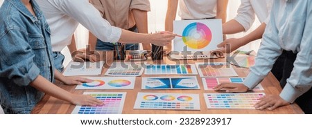 Graphic designer brainstorm logo and graphic art at busy creative studio workshop. Experiment and brainstorm color palette and pattern at workspace table for creative design. Panorama shot. Scrutinize