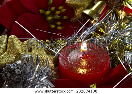 Picture of a Christmas candle decorated with stars, bells and poinsettia.