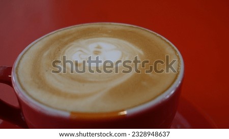 This is the picture of a cup of cappuccino in a red cup.