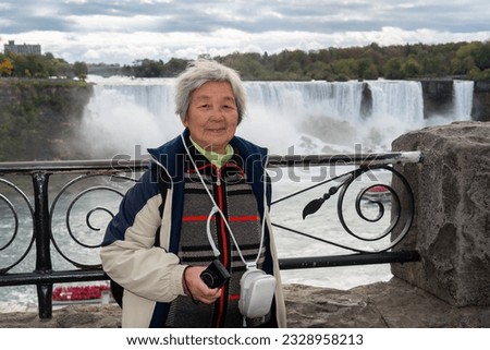 Mature Chinese tourist posing for photos at Niagara Falls, Ontario. Canada. 