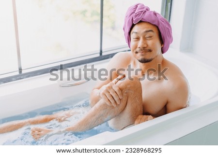 Funny asian man being childish and playful in the bathtub.