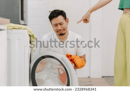 Sad husband being told to wash clothes by his wife. Funny asian couple. Royalty-Free Stock Photo #2328968341