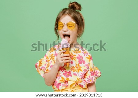 Little cute child kid girl 6-7 years old wearing casual clothes sunglasses eat icecream have fun isolated on plain pastel green background studio portrait. Mother's Day love family lifestyle concept
