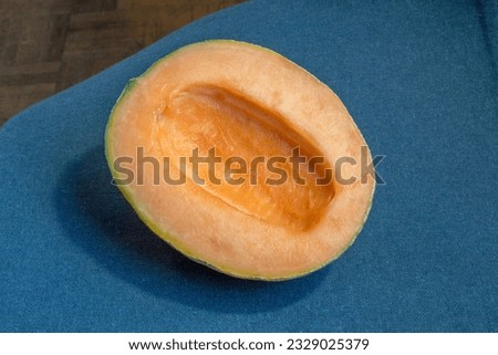 A close-up photo of a fresh and enticing cantaloupe melon, accentuated by a dark blue woven cloth backdrop. The top view captures its refreshing appeal.