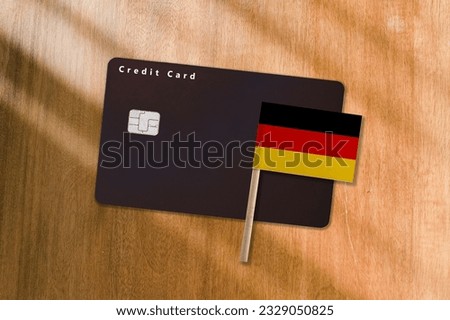 The Flag of Germany and Black Credit Card on Wooden Background.