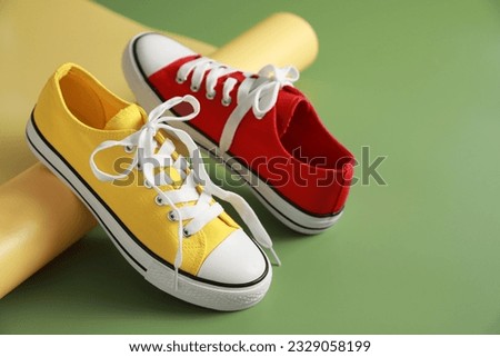 Stylish presentation of red and yellow classic old school sneakers on green background. Space for text