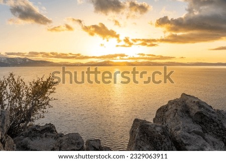 Sunset view from the Cave Rock at Lake Tahoe and nearby road, Nevada, with snowy Sierra Nevada Mountains in the background.