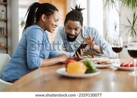 Happy African American couple using a  phone while having breakfast in the morning.