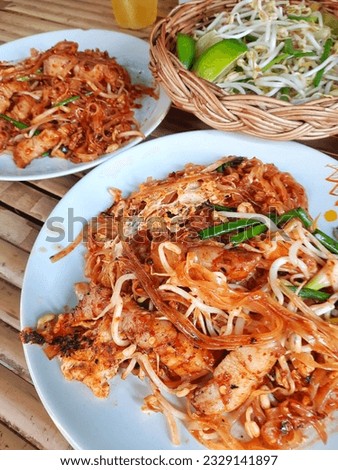 Thai food, 2 plates of stir-fried noodles with pork belly, bean sprouts in a basket and tea