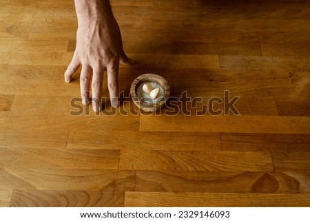 Man's hand holding a wooden bowl of garlic on a wooden background Royalty-Free Stock Photo #2329146093