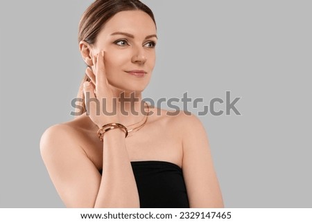 Beautiful woman with elegant jewelry on light grey background. Space for text