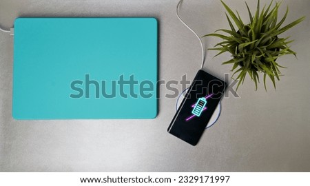 Charging mobile phone battery with wireless charging device on the table.