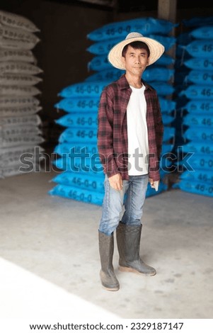 Asian farmer man wear red shirt standing with chemical fertilizer sack at warehouse
