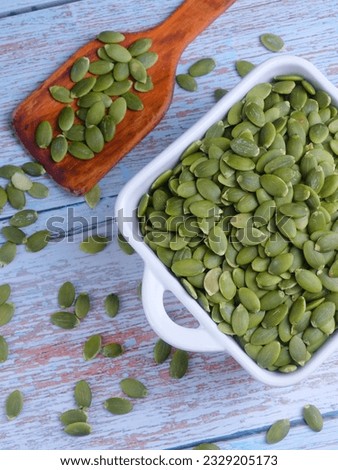 Pumpkin seeds. Still life for advertising photography for online store or marketplace. Peeled pumpkin seeds in plate on wooden table. Top view.