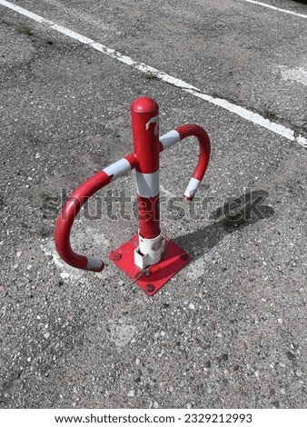 A red metal colored barrier to stop parking, an obstacle for parking with a key, parking stop sign for people with do not have a key, blockade the exit from parking for not paying, space