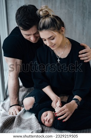 Young pretty people with newborn baby. Happy parents watching their baby sleeping at home.