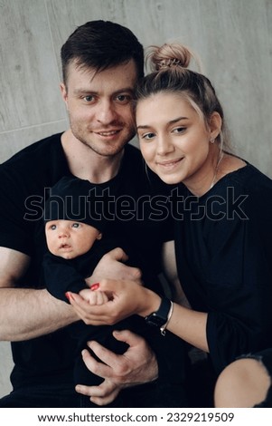 Smilling parents with their baby at home. Pretty young family with newborn baby.
