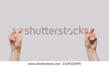 Air quotes. Sarcasm gesture. Woman hands showing quotation marks vitriol bending fingers isolated on gray empty space background.