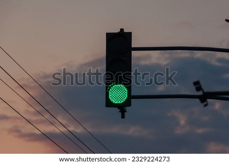  Green traffic light on sunset background.