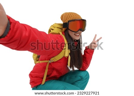 Smiling woman in ski goggles taking selfie and showing peace sign on white background