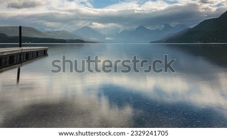 Sunrise on Lake McDonald in Glacier National Park in Montana.  Strong sky reflection on the still water.  Empty dock extending into the lake. Royalty-Free Stock Photo #2329241705