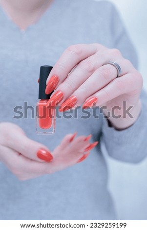 Female beautiful hand with long nails and a bright orange nail polish