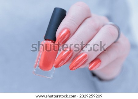 Female beautiful hand with long nails and a bright orange nail polish