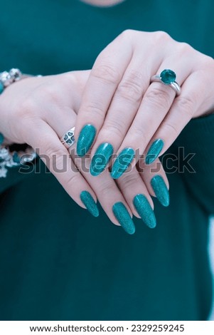 Woman's hand with long nails and emerald green nail polish