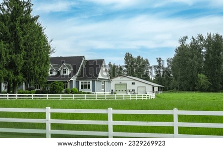 North American Farm country house in the field with fence. Countryside of Canada. Rural Farmhouse with barns on a sunny day in a summer.Beautiful house entrance with a garden and green lawn Royalty-Free Stock Photo #2329269923
