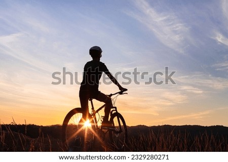 Silhouette of a man riding his mountain bike with sunset in the background