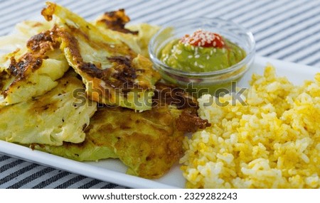 Vegetarian dish of leaves of cabbage in batter with rice and green pea sauce