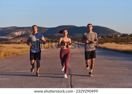 A group of young athletes running together in the early morning light of the sunrise, showcasing their collective energy, determination, and unity  Royalty-Free Stock Photo #2329290499