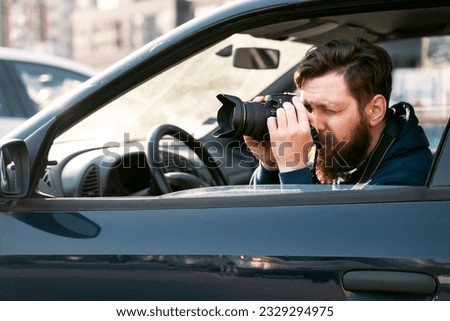 Man paparazzo taking pictures from the car, closeup shot . Private investigator