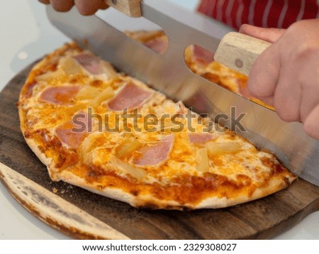 Closeup chef cuts freshly prepared pizza slices. Hand of chef baker in white uniform cutting pizza at kitchen. Pizza picture free space for text.