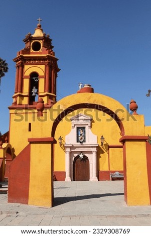 Peña de Bernal Church. A colorful catholic church with a bell tower and arches that allow the entrance to the church. Yellow and orange church in te touristic magical town of Peña de Bernal in Mexico. Royalty-Free Stock Photo #2329308769