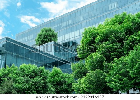 Eco-friendly building in the modern city. Sustainable glass office building with trees for reducing heat and carbon dioxide. Office building with green environment. Corporate building reduce CO2.  Royalty-Free Stock Photo #2329316137