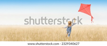 Little girl runs outdoors. Cheerful and happy child plays and launches a kite in the field against the blue sky. Kid dreams of flying and aviation. Royalty-Free Stock Photo #2329340627