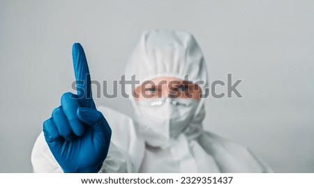 Doctor warning. Healthcare professional. Woman virologist nurse in white protective equipment mask gloves attention hand sign isolated on grey background. Royalty-Free Stock Photo #2329351437