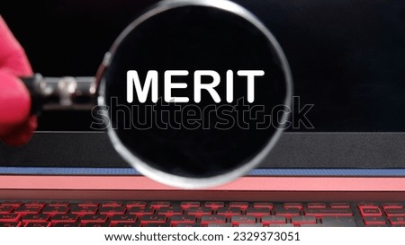 A symbol of merit. The conceptual word merit through a magnifying glass on a black laptop monitor. The concept of business and merit.