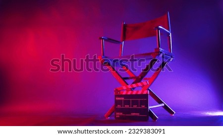 Director chair and clapper board in red and blue light color with black background Royalty-Free Stock Photo #2329383091