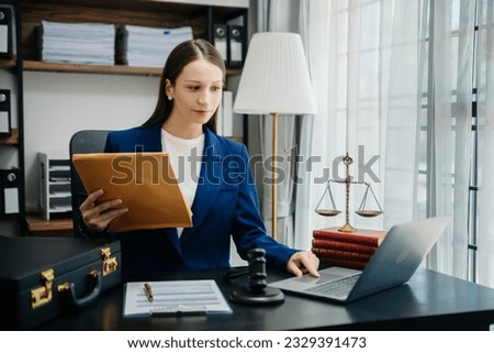 justice and law concept. Female judge in a courtroom  the gavel, working with smart phone and laptop and digital tablet computer on wood table in morning light 
